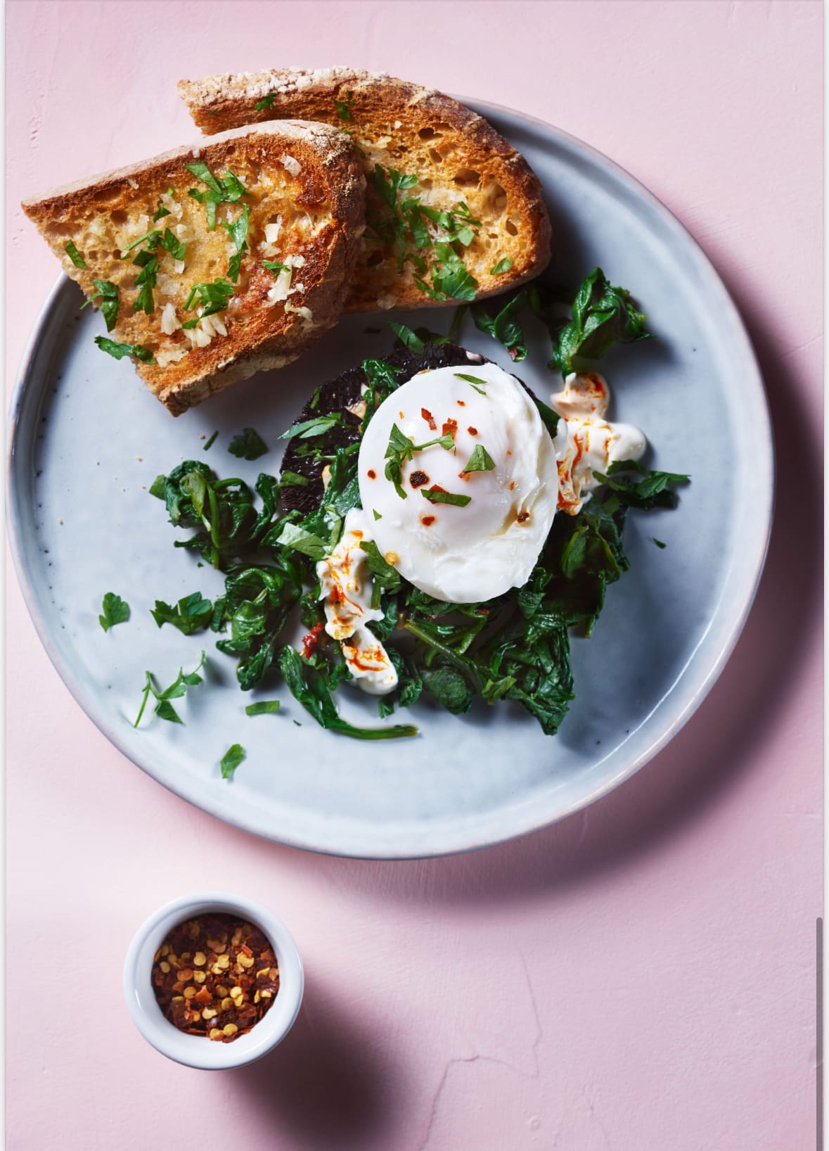 Plate of Greek poached eggs with spinach, yogurt, garlicky mushrooms, and chili flakes.